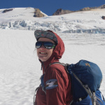 Mariama (woman with pale skin and brown hair, wearing a hat and bundled up in a jacket) stands on a glacier in the North Cascades